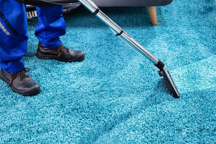 Close-up Of A Person Cleaning Carpet With Vacuum Cleaner
